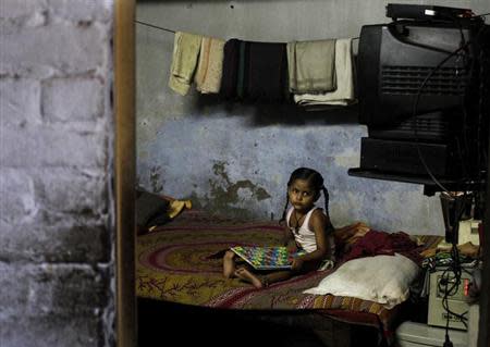 A girl plays a game inside her home at a slum in New Delhi September 23, 2013. REUTERS/Anindito Mukherjee/Files