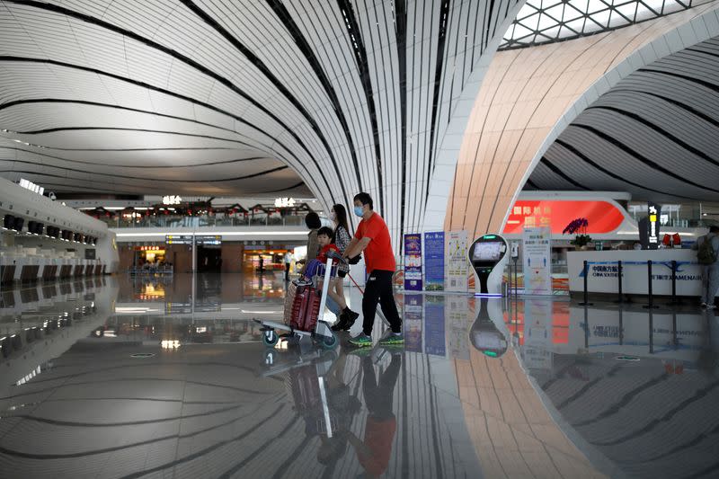 Passengers wearing face masks following the coronavirus disease (COVID-19) outbreak walk with luggages at a terminal hall of the Beijing Daxing International Airport ahead of Chinese National Day holiday, in Beijing