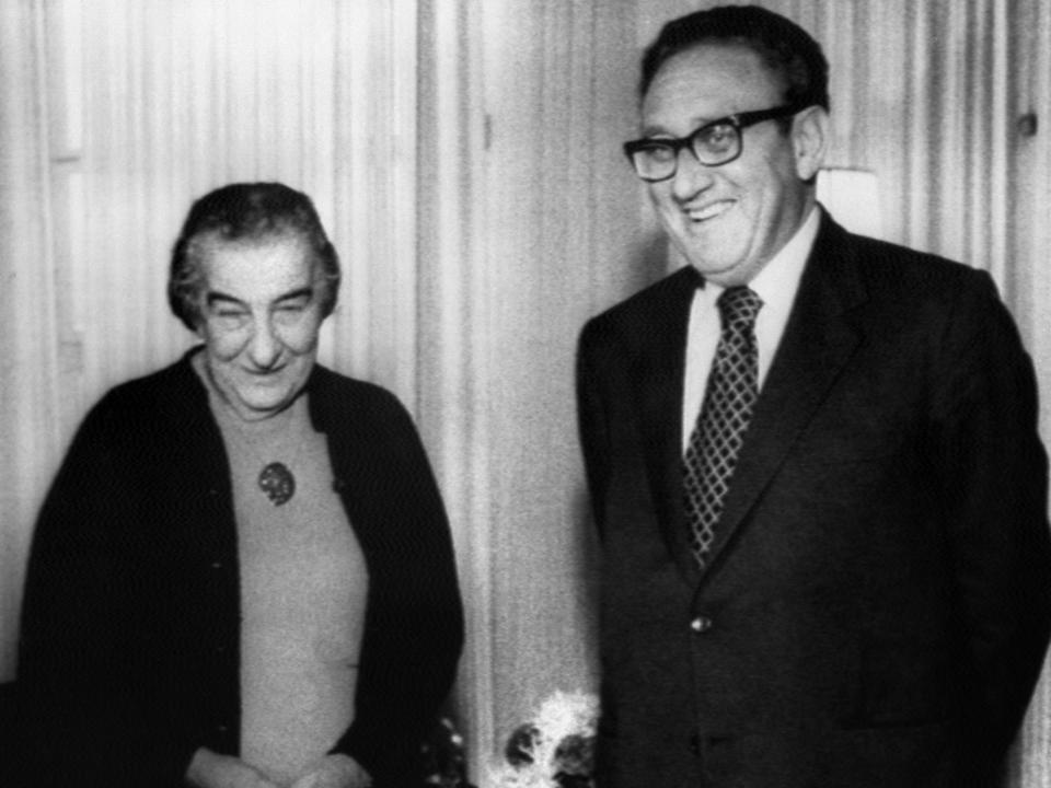 A black and white photo of American Secretary of State Henry Kissinger (Right) standing next to Israeli Prime Minister Golda Meir (Left