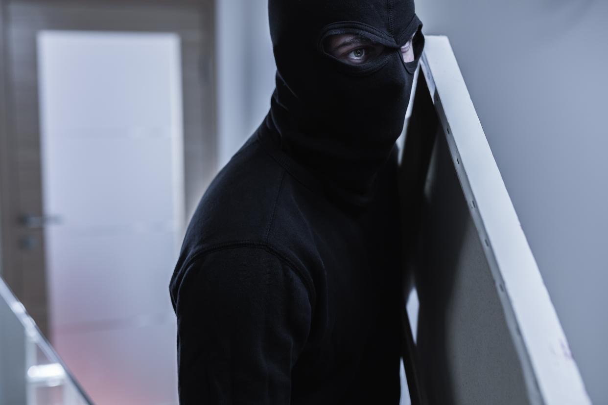 Close-up of robber in balaclava stealing painting