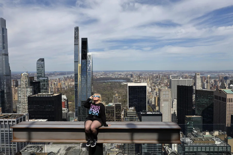  Laura Holden poses for a photo wearing eclipse glasses from Top of the Rock at Rockefeller Center in New York. (Michael M. Santiago / Getty Images)