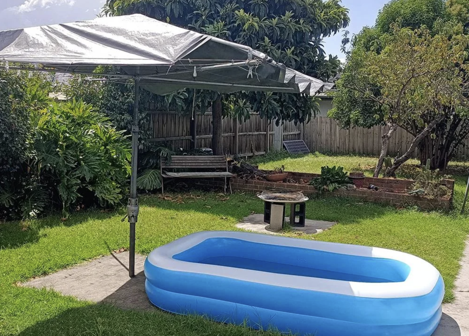 A baby pool outside under a clothes line.