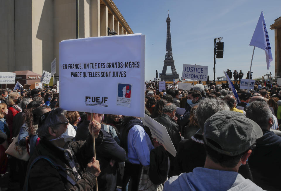 A man holds a placard that reads, "in France grandmothers are killed because they are jews," during a protest organized by Jewish associations, who say justice has not been done for the killing of French Jewish woman Sarah Halimi, at Trocadero Plaza near Eiffel Tower in Paris, Sunday, April 25, 2021. Thousands of people have gathered in Paris and other French cities to denounce a ruling by France's highest court that the killer of Jewish woman Sarah Halimi was not criminally responsible and therefore could not go on trial. Eiffel Tower in the background. (AP Photo/Michel Euler)