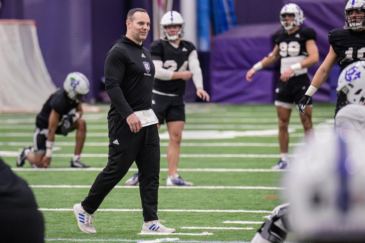 Holy Cross coach Dan Curran walks through stretches during warmups at football spring practice Tuesday.