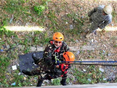 A Filipino soldier uses a harness to carry a mock victim while a U.S. military soldier looks on, as part of an earthquake scenario during the Philippines and United States annual Balikatan (shoulder to shoulder) exercises inside the Fort Magsaysay military headquarters in Nueva Ecija province, north of Manila, Philippines May 12, 2017. REUTERS/Romeo Ranoco