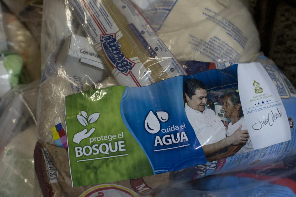 FILE - This Oct. 30, 2018 file photo shows "solidarity bags" of basic goods that include rice, dried spaghetti and sugar, covered by a photo of Honduran President Juan Orlando Hernandez and a note saying it comes from his government, at a migrant care center at the main bus terminal in San Pedro Sula, Honduras. Many Hondurans blame their country's problems on the president who was re-elected in 2018 despite a constitutional ban on second terms and in a vote that was marred by irregularities. (AP Photo/Moises Castillo, File)
