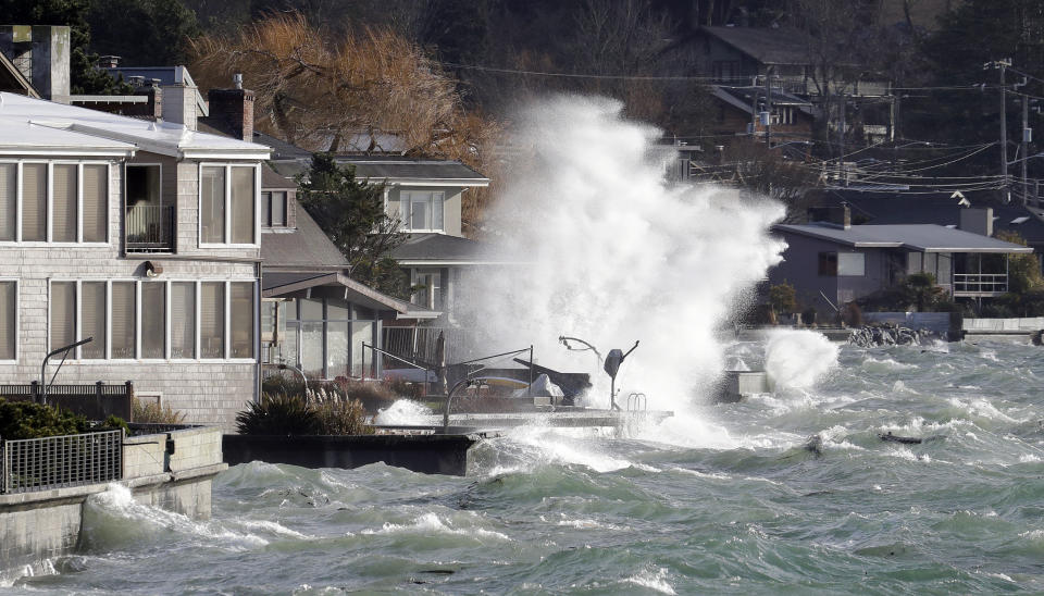 Waves crash against a seawall next to homes at high tide during a windstorm Thursday, Dec. 20, 2018, in Seattle. More than 140,000 households and businesses lost power Thursday as strong winds toppled trees, closed roads and even trapped a trampoline between power lines in western Washington. A high wind warning remained in effect for much of area into Thursday evening, with gusts up to 60 miles an hour recorded earlier in the day. (AP Photo/Elaine Thompson)