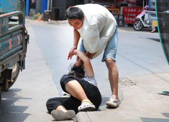 He then drags her by the hair along the pavement. (Photo: chinaSMACK.com)