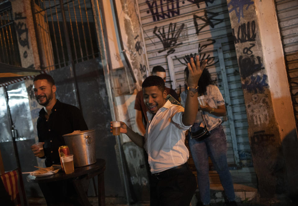 A man dances during a street performance by the Brazilian band Atitude Nossa as the restrictions related to the COVID-19 pandemic are eased in Rio de Janeiro, Brazil, Monday, Oct. 5, 2020. Since the beginning of October, live shows are now permitted in Rio de Janeiro. (AP Photo/Silvia Izquierdo)