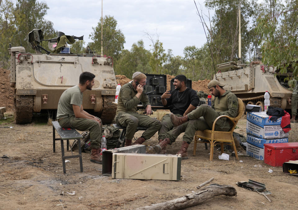 Israeli soldiers sit together near the Israel-Gaza border in southern Israel, Saturday, Nov. 25, 2023. Hamas was preparing to release more than a dozen hostages Saturday for several dozen Palestinian prisoners held by Israel, part of an exchange on the second day of a cease-fire. AP Photo/Tsafrir Abayov)