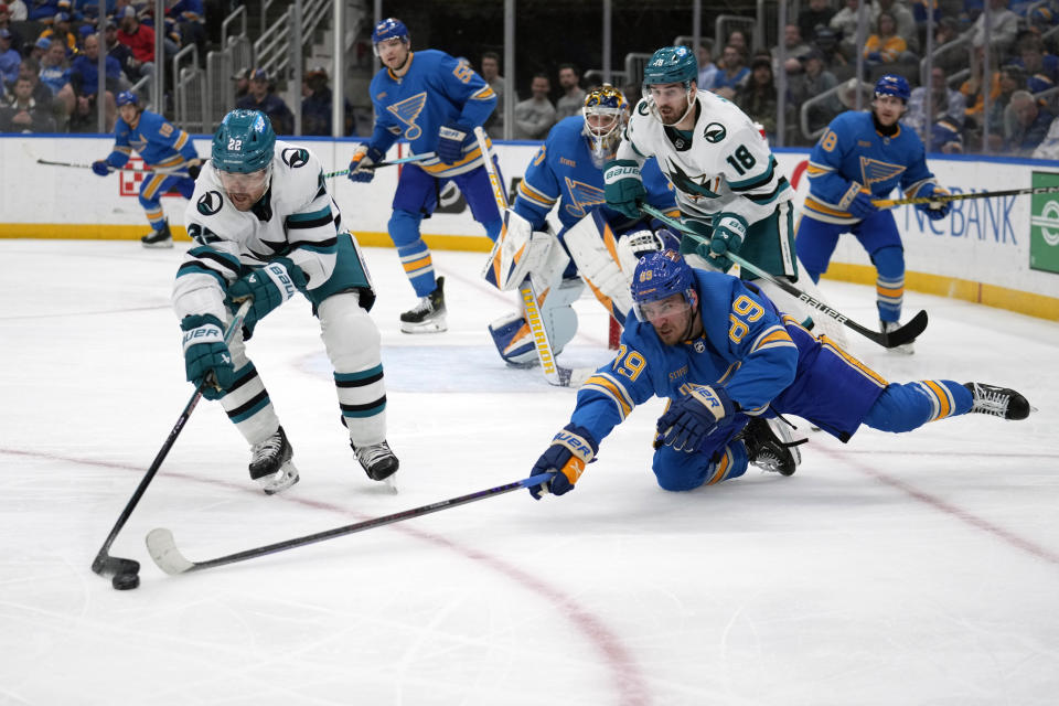 St. Louis Blues' Pavel Buchnevich (89) and San Jose Sharks' Ryan Carpenter (22) reach for a loose puck during the third period of an NHL hockey game Saturday, March 30, 2024, in St. Louis. (AP Photo/Jeff Roberson)