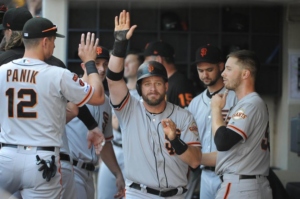 San Francisco Giants catcher Stephen Vogt (21) receives high-fives in the dugout after scoring a seventh-inning run against the Milwaukee Brewers at Miller Park, July 14, 2019, in Milwaukee.