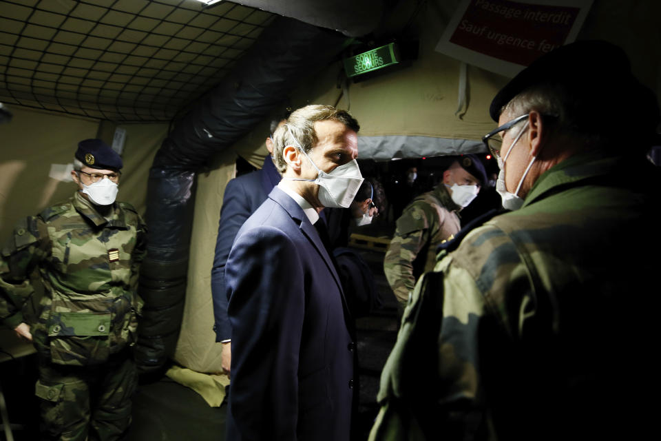 French President Emmanuel Macron, center, wears a face mask as he visits the military field hospital in Mulhouse, eastern France, Wednesday, March 25, 2020. French President Emmanuel Macron launched a special military operation Wednesday to help fight the new virus in one of the world's hardest-hit countries. The new coronavirus causes mild or moderate symptoms for most people, but for some, especially older adults and people with existing health problems, it can cause more severe illness or death. (Mathieu Cugnot/Pool via AP)