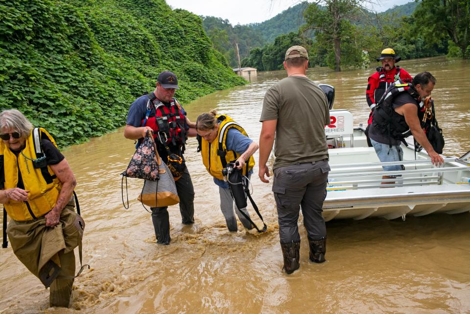 Members of a rescue team assist a family out of a boat on July 28, 2022 in Quicksand, Kentucky. Storms that dropped as much as 12 inches of rain in some parts of Eastern Kentucky have caused devastating floods in some areas and have claimed at least eight lives.