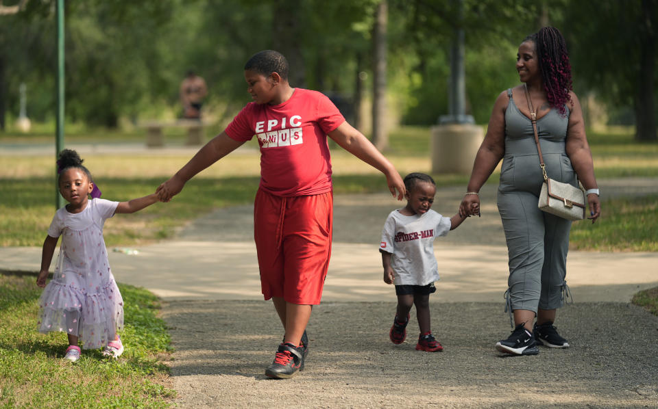 Tamika Davis, right, walks through MLK Park with three of her children, from left, Shanara, 3, Matthew, 11, and Lionel Jr., 2, in San Antonio, Thursday, May 30, 2024. Davis said friends and family watched her kids for most of her doctor visits during treatment last year for colon cancer. But she couldn't afford additional childcare, and she didn't know where to look for assistance. (AP Photo/Eric Gay)