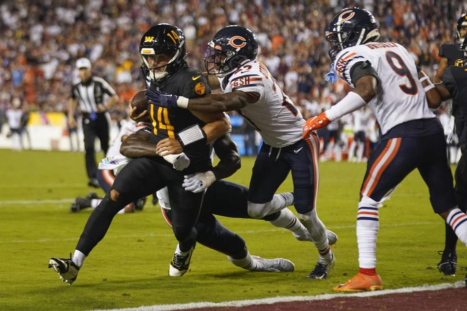 Washington Commanders quarterback Sam Howell (14) runs with the ball to score on a two-point conversion against Chicago Bears cornerback Greg Stroman Jr. (27), defensive end Yannick Ngakoue (91) and safety Jaquan Brisker (9) during the second half of an NFL football game, Thursday, Oct. 5, 2023, in Landover, Md. (AP Photo/Andrew Harnik)