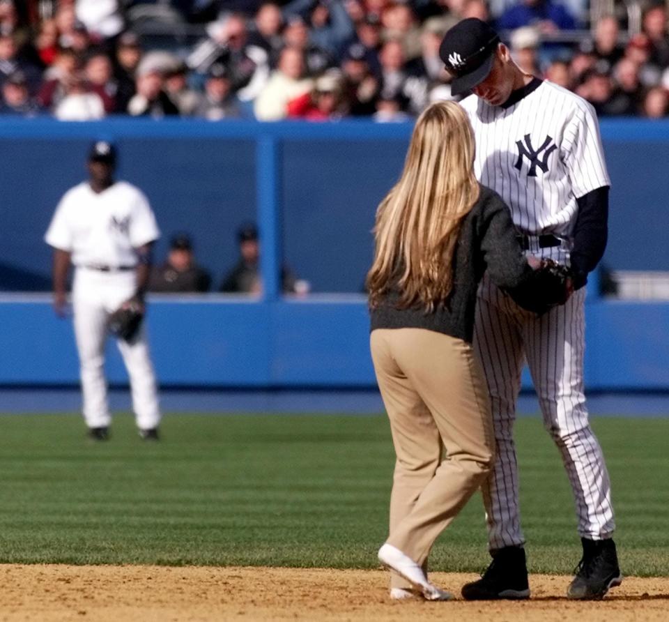 A fan who ran onto the field hands New York Yankee shortstop Derek Jeter a piece of paper before running back of the field 05 April 2002 at Yankee Stadium Opening Day in the Bronx, NY. The Yankees beat the Devil Rays 4-0. (Photo by Matt Campbell/AFP/Getty Images)