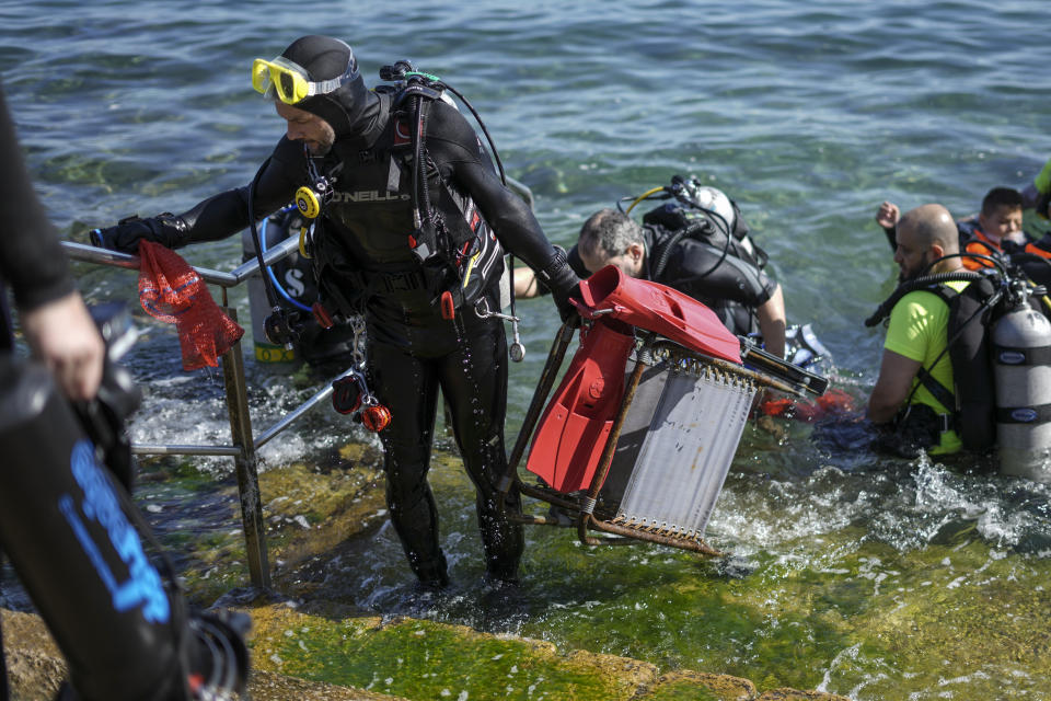 A scuba-diving volunteer comes out of the water holding a chair he collected during World Ocean Day event in the Mediterranean ancient Caesarea's Roman-period port, Israel, Friday, June 10, 2022. Divers visiting the ancient seaport of Caesarea on Israel's Mediterranean coast occasionally find treasure, but on Friday they searched for trash. Twenty six scuba-diving volunteers removed around 100 pounds (45 kilograms) of garbage from between the sunken pillars and submerged ruins of the historic site as part of a United Nations World Oceans Day initiative. (AP Photo/Ariel Schalit)