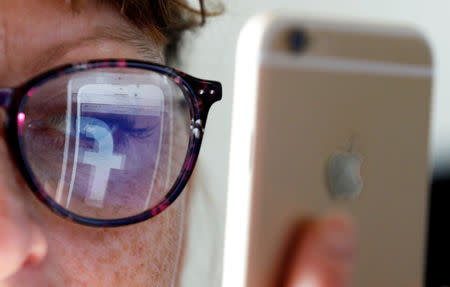 The Facebook logo is reflected on a woman's glasses in this photo illustration taken June 3, 2018. REUTERS/Regis Duvignau/Illustration