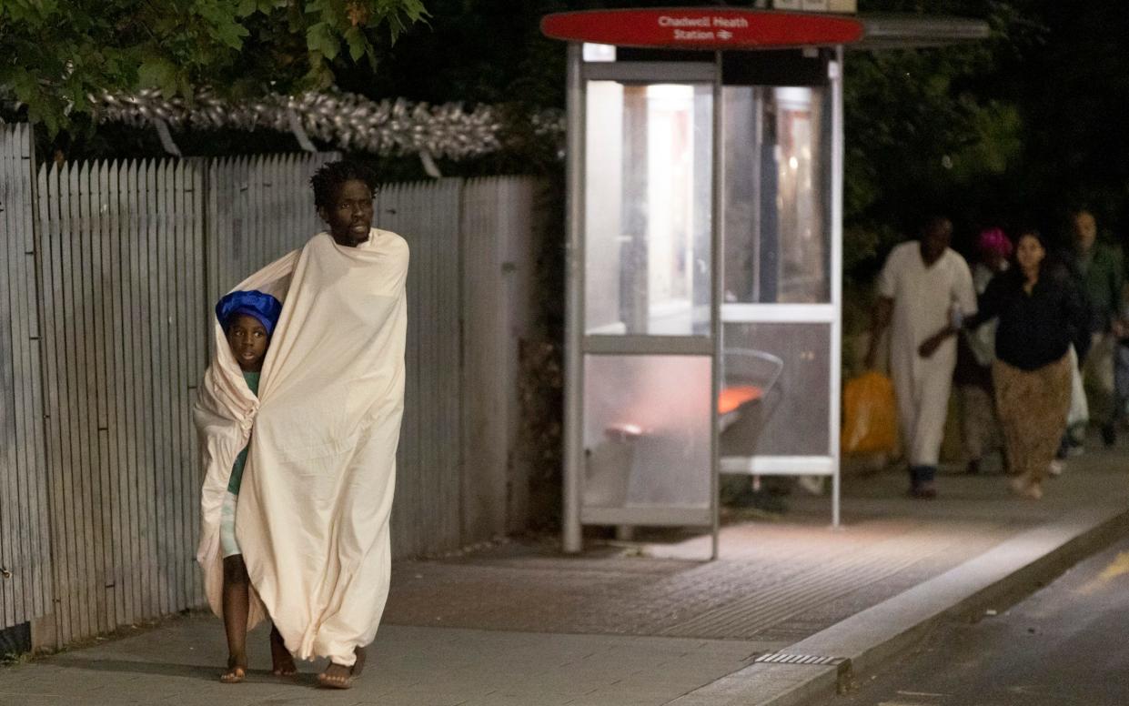 Barefoot Dagenham flat residents wrapped in a sheet are evacuated after large fire broke out in their tower block