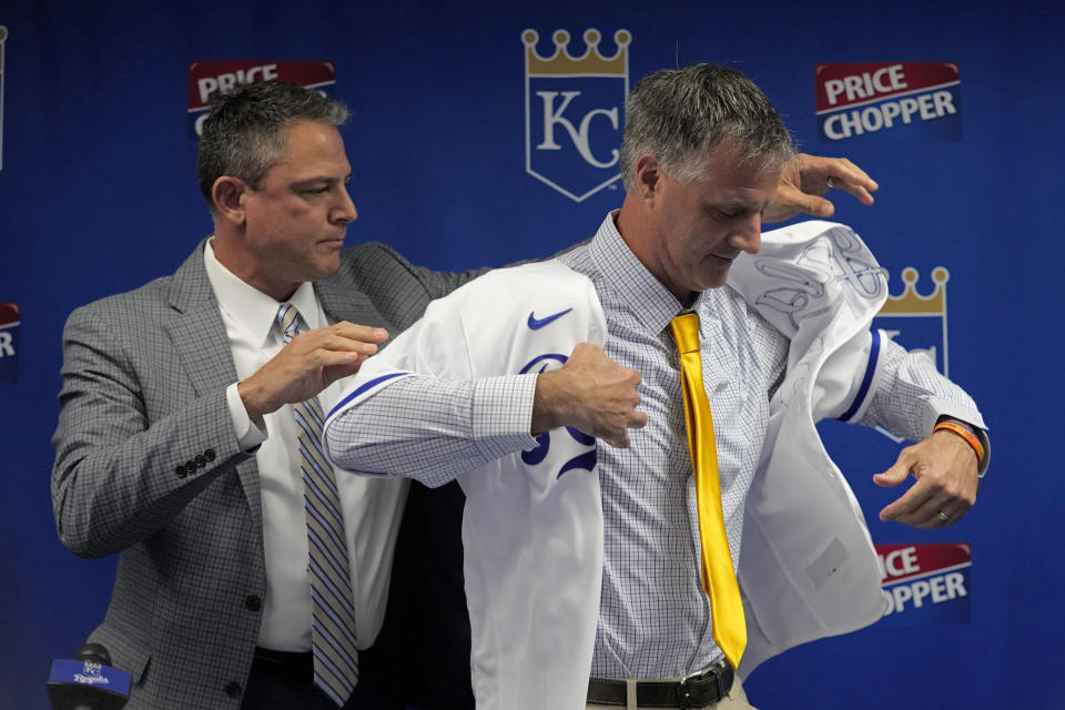 Matt Quatraro is helped by general manager J.J. Piccolo as he tries on a jersey during a news conference announcing him as the new manager of the Kansas City Royals Thursday, Nov. 3, 2022, in Kansas City, Mo. (AP Photo/Charlie Riedel)