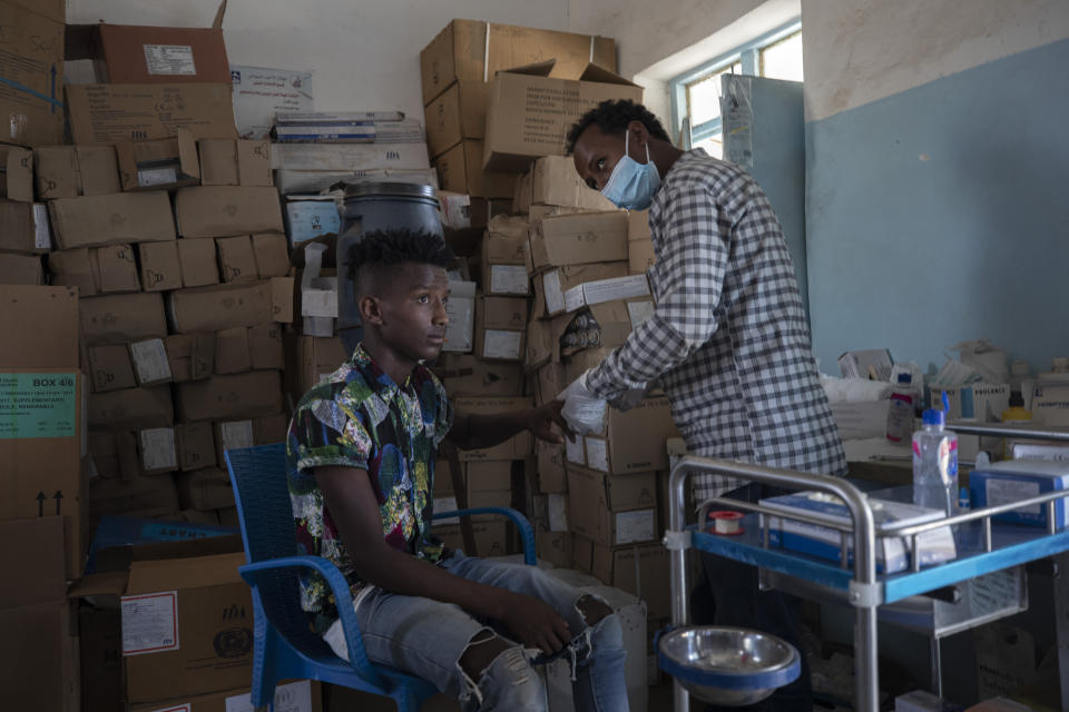 Seid Mussa Omar, a 29-year-old Tigrayan nurse from Humera, treats a man at the Sudanese Red Crescent clinic, in Hamdayet, eastern Sudan, near the border with Ethiopia, on March 17, 2021. Amhara authorities now in charge took Omar's original ID card displaying his Tigrayan ethnicity and burned it, he said. On the new card examined by the AP, traces of Tigray had vanished. It was issued in January 2021 in a city located so far north in Ethiopia that it is within sight of neighboring Eritrea. Yet the card is stamped by authorities of the Amhara region to the south. The language on the card is Amharic, not the Tigrinya of Tigray. (AP Photo/Nariman El-Mofty)