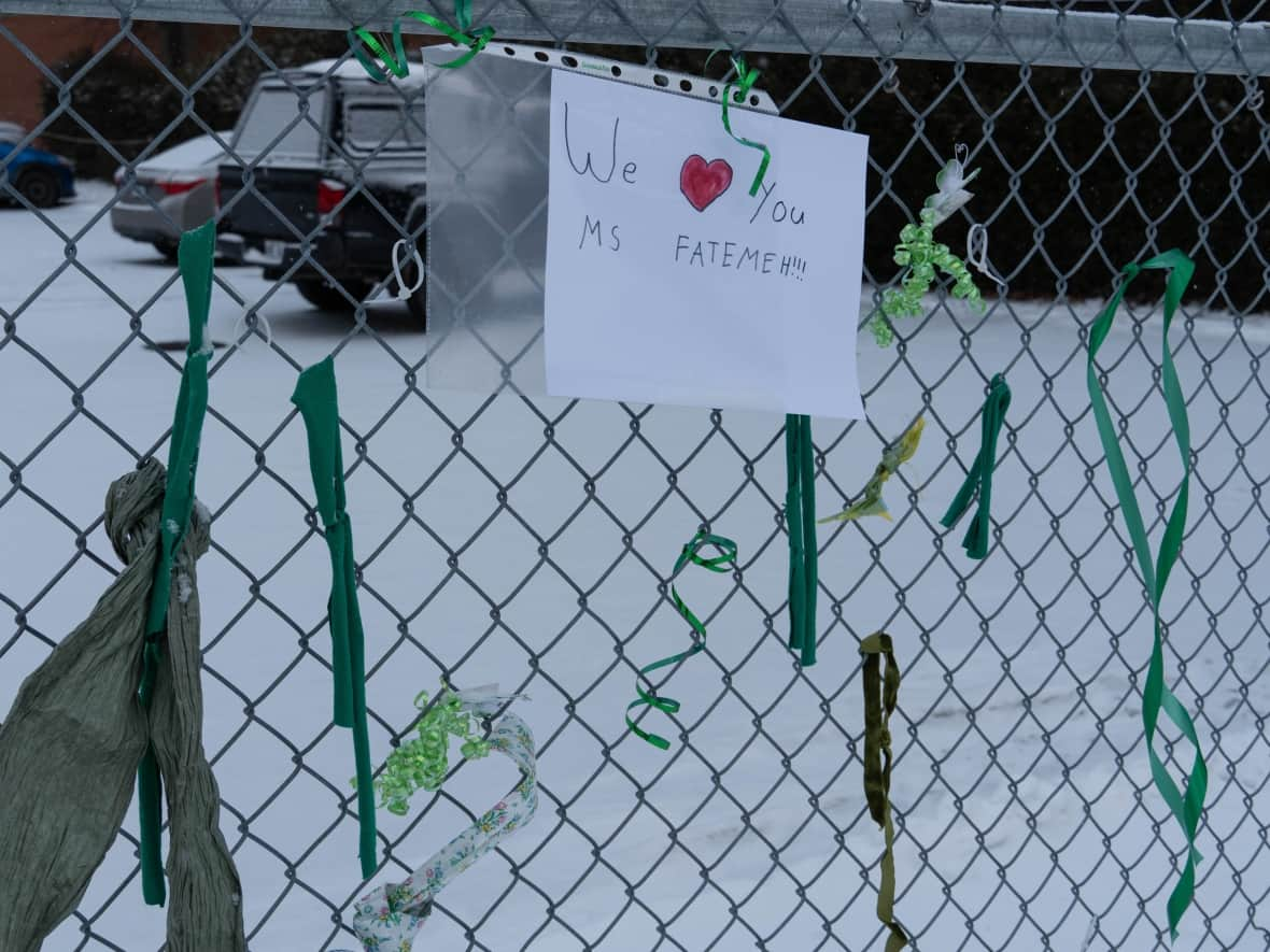 A hand-drawn poster in support of teacher Fatemeh Anvari is surrounded by green ribbons on a chain-link fence outside Chelsea Elementary School in Chelsea, Que. Recently, the school principal told the Grade 3 teacher she had to move to a position outside the classroom because she wears a hijab. Under Quebec's Bill 21, some civil servants — including teachers — can't wear religious symbols at work. (Jean Delisle/CBC - image credit)