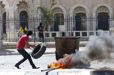 A Palestinian protester places a tyre into fire during clashes with Israeli troops at a protest against the Israeli offensive in Gaza, in the West Bank town of Bethlehem August 1, 2014. REUTERS/Ammar Awad