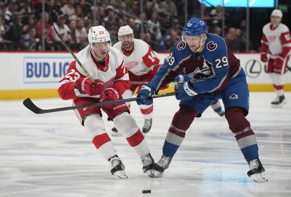 Detroit Red Wings left wing Lucas Raymond (23) pursues the puck with Colorado Avalanche center Nathan MacKinnon (29) in the second period of an NHL hockey game Monday, Jan. 16, 2023, in Denver. (AP Photo/David Zalubowski)