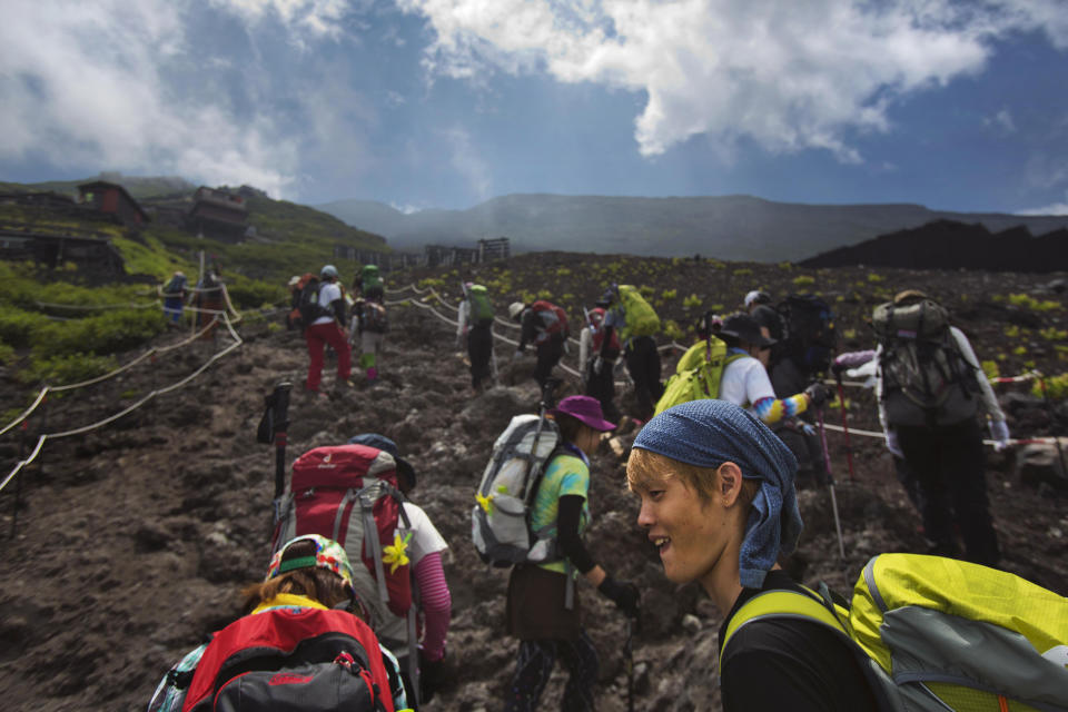 In this Saturday, Aug. 10, 2013 photo, Japanese hikers climb one of the trails on Mount Fuji. The recent recognition of the 3,776-meter (12,388-foot) peak as a UNESCO World Heritage site has many here worried that will draw still more people, adding to the wear and tear on the environment from the more than 300,000 who already climb the mountain each year. (AP Photo/David Guttenfelder)