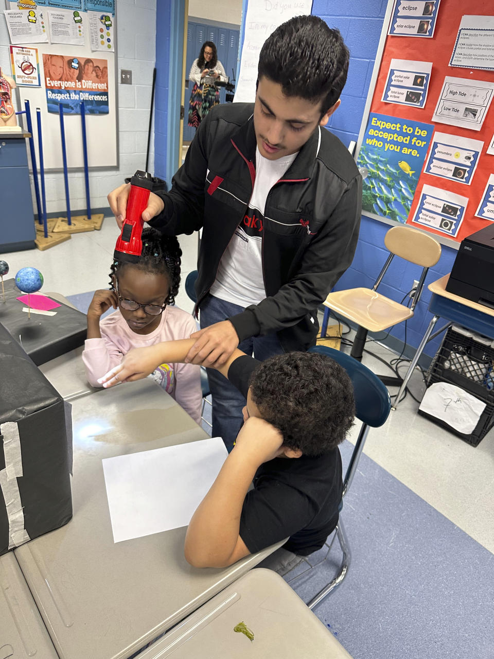 Abdulrahman Aljabri, 14, uses a flashlight as students experiment with shadows at Riverside Elementary School in Cleveland on March 14, 2024. Students are learning about the upcoming total solar eclipse, a topic that has challenged and inspired teachers in and near the eclipse's path. (AP Photo/Carolyn Thompson)