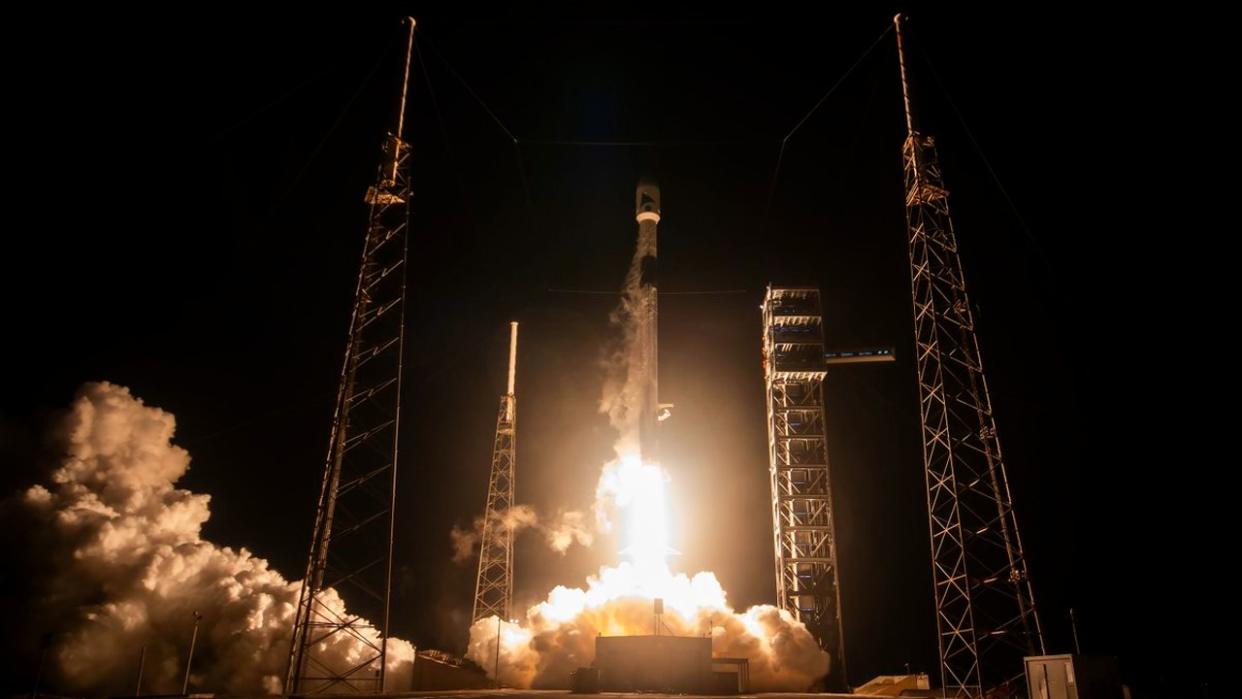  A rocket lifts off a launch pad at night above a bright plume of fire and smoke. 