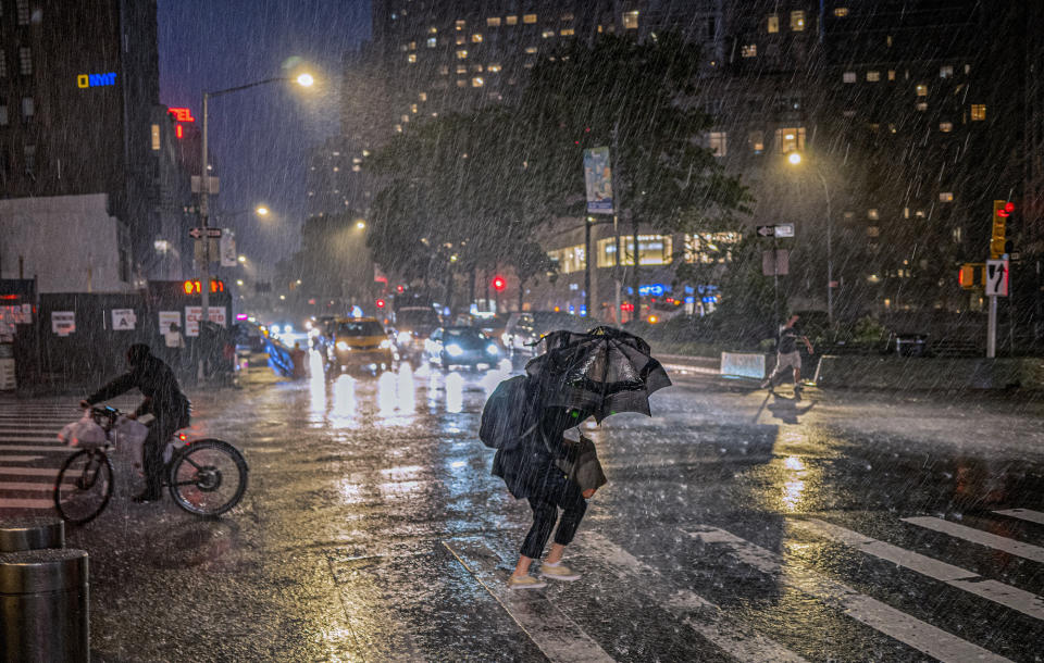 People travel through a torrential downpour caused from the remnants of Hurricane Ida, near Columbus Circle on Sept. 1, 2021. As weather becomes more extreme and unpredictable caused by climate change, transit officials say that more needs to be done to prepare the East Coast's vital transit systems. (AP Photo/Craig Ruttle)