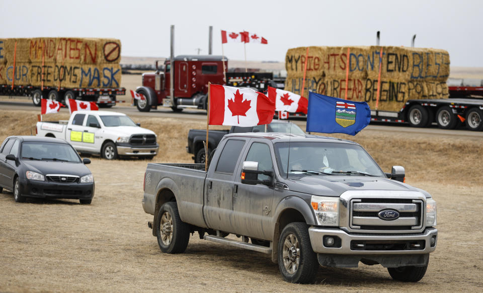 Anti-COVID-19 vaccine mandate demonstrators gather as a truck convoy blocks the highway at the busy U.S. border crossing in Coutts, Alberta, Canada, Monday, Jan. 31, 2022. (Jeff McIntosh/The Canadian Press via AP)