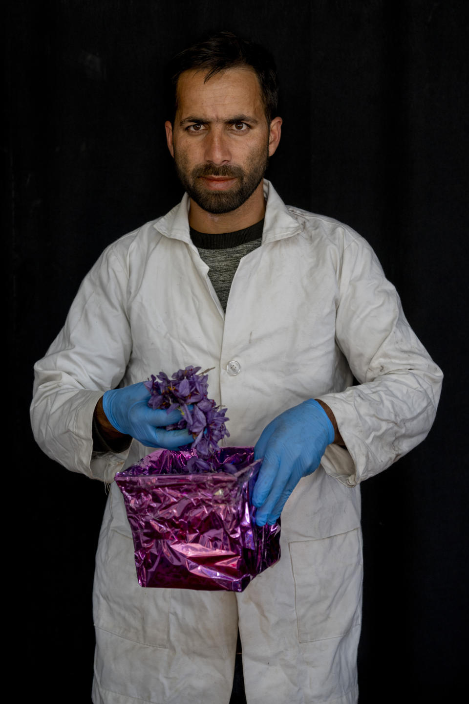 Shakir Ahmad Bhat, an employee of Advance Research Station For Saffron & Seed Spices poses for a photograph as he holds the basket full of crocus flowers, the stigma of which produces saffron, in Dussu, south of Srinagar, Indian controlled Kashmir, on Oct. 29, 2022.As climate change impacts the production of prized saffron in Indian-controlled Kashmir, scientists are shifting to a largely new technique for growing one of the world’s most expensive spices in the Himalayan region: indoor cultivation. (AP Photo/Dar Yasin)