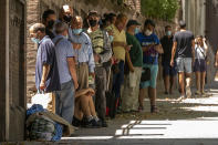 People queue to receive donated food in Madrid, Spain, Thursday, Aug. 5, 2021. Food requests have increased considerably in the last months due to the coronavirus pandemic. (AP Photo/Andrea Comas)