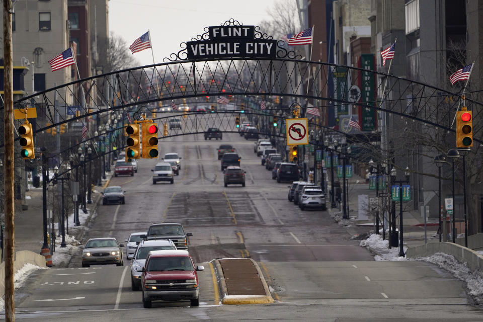 FILE - In this Jan. 13, 2021 file photo, vehicles drive through downtown Flint, Mich. A judge granted preliminary approval Thursday, Jan. 21, 2021, to a $641 million deal that would benefit Flint residents who were harmed by lead-contaminated water. The settlement includes $600 million from the state of Michigan, although Flint, an area hospital and an engineering firm are also part of the agreement. (AP Photo/Paul Sancya File)