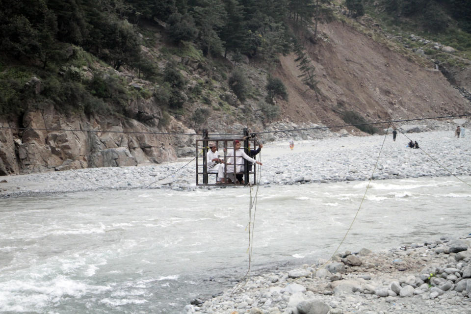 People cross a river on a suspended cradle, in Kalam Valley in northern Pakistan, Friday, Sept. 9, 2022. Guterres appealed to the world for help for cash-strapped Pakistan after arriving in the country Friday to see the climate-induced devastation from months of deadly record floods. (AP Photo/Naveed Ali)