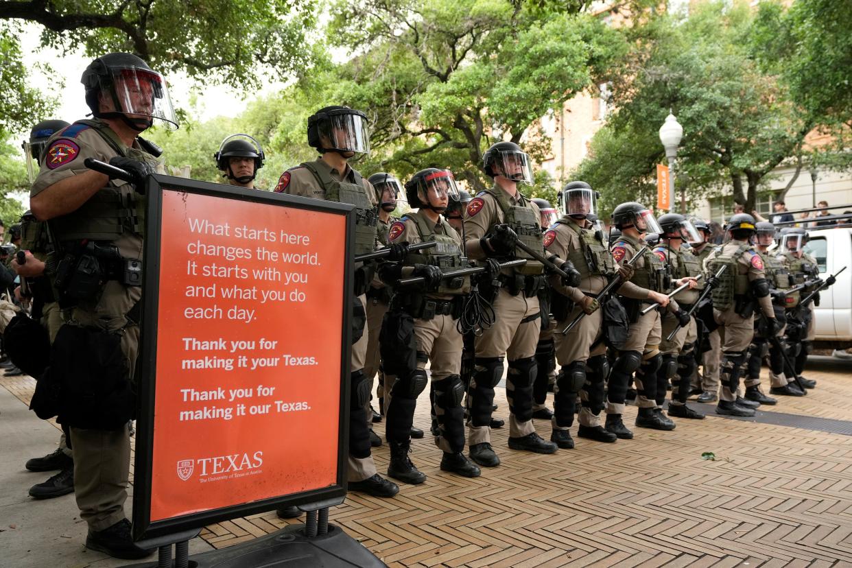 Texas Department of Public Safety troopers deploy to stop a campus protest Wednesday while standing next to a University of Texas sign.