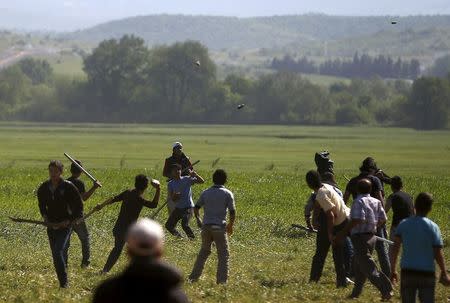 Men throw stones and fight with sticks during a scuffle, which started at a food distribution queue, at a makeshift camp for migrants and refugees at the Greek-Macedonian border near the village of Idomeni, Greece, April 20, 2016. REUTERS/Stoyan Nenov