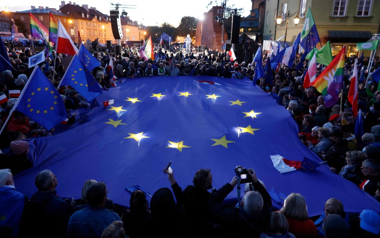 Participants hold a large EU flag as they take part in a pro-EU demonstration following a ruling of the Constitutional Court against the primacy of EU law in Poland, in Warsaw - WOJTEK RADWANSKI/AFP