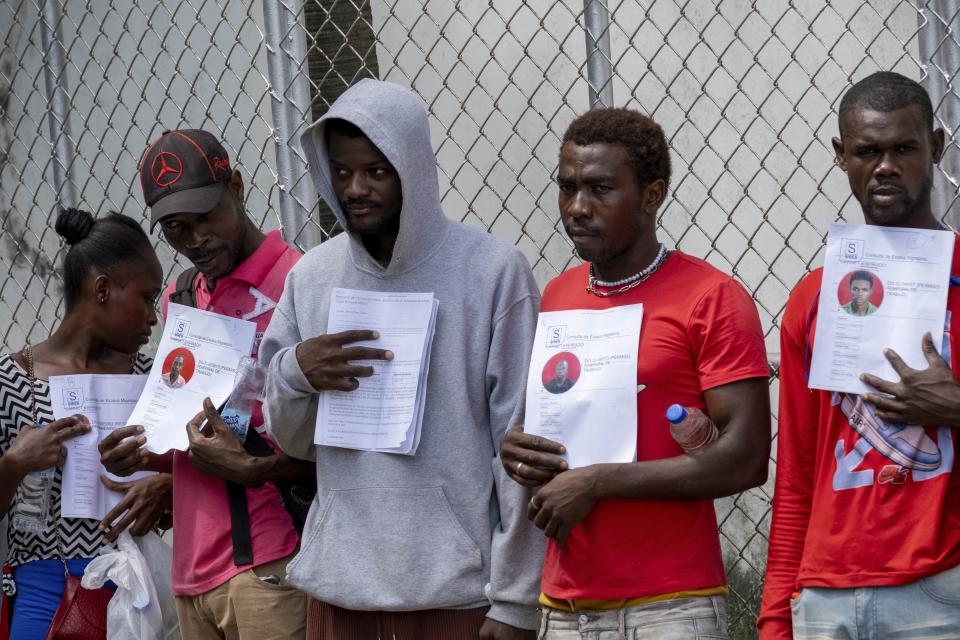 FILE - Haitians hold up their immigration status documents to prove they have work permits, in Haina, Dominican Republic, March 16, 2024. Dominican Republic’s election on Sunday, May 19, has been defined by calls for more migratory crackdowns and finishing a border wall dividing the countries. (AP Photo/Ricardo Hernandez, File)