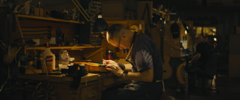 Repair person Dana Atkinson assessing a broken stringed instrument (Breakwater Studio)