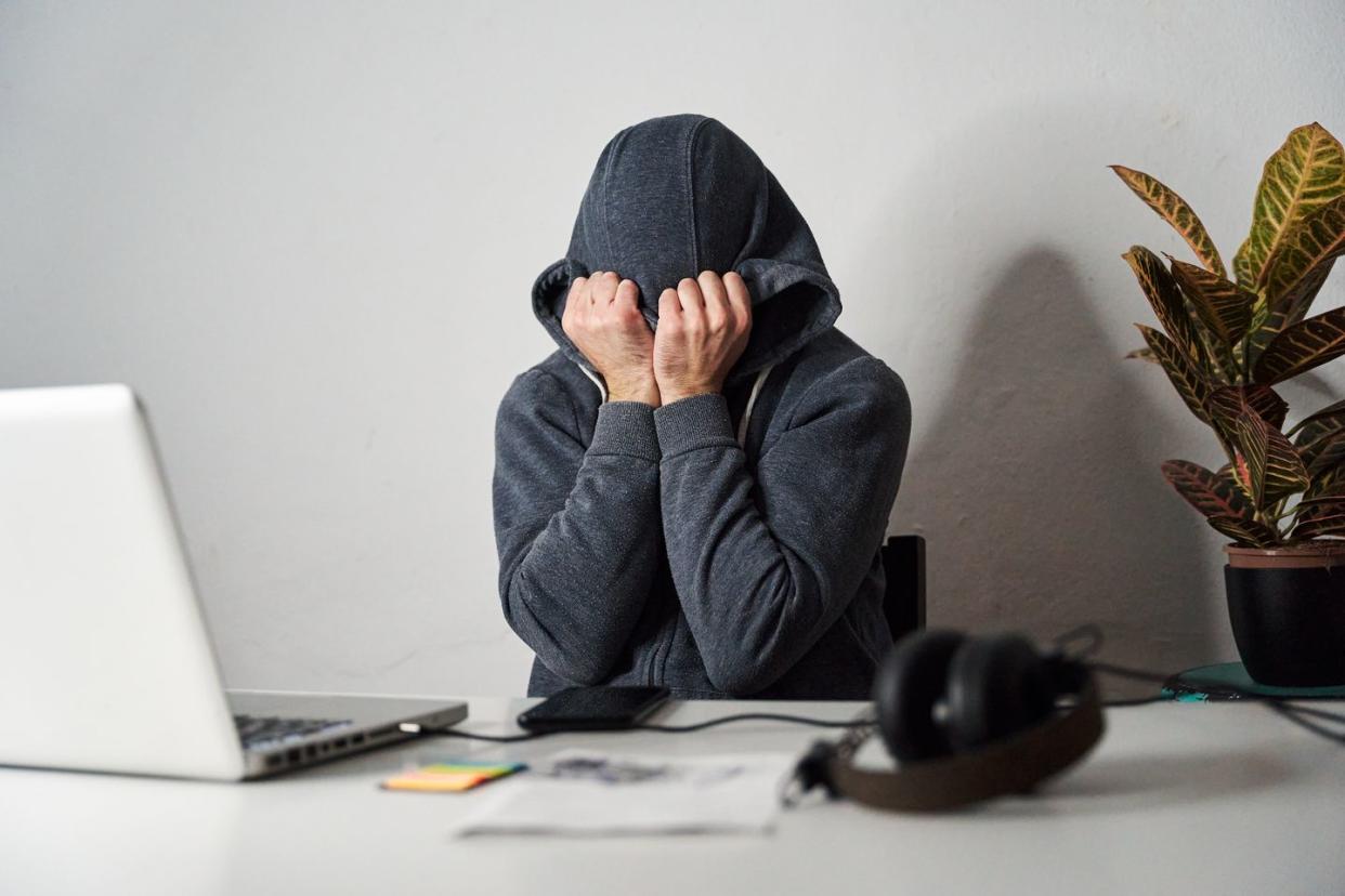 tired man covering his face with a hood while working from home