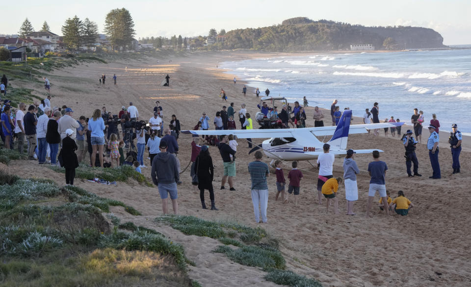 People stand near a light plane that made an emergency landing on a beach in Sydney Wednesday, May 26, 2021. The recreational plane landed safely on a Sydney beach with three people aboard including a baby on Wednesday after its single engine failed, officials said. (AP Photo/Mark Baker)