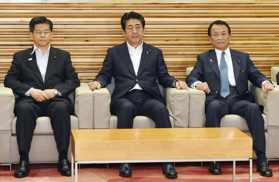 FILE - In this Aug. 2, 2019, file photo, Japan's Prime Minister Shinzo Abe, center, sits with Transport Minister Keiichi Ishii, left, and Finance Minister Taro Aso to attend a Cabinet meeting to decide to downgrade South Korea’s trade status, in Tokyo. South Korea has threatened to end a military intelligence sharing agreement with Japan as their tensions escalate over export controls. The agreement, known as GSOMIA, is a symbol of the countries’ trilateral security cooperation with their ally United States in the region. (Yoshitaka Sugawara/Kyodo News via AP, File)