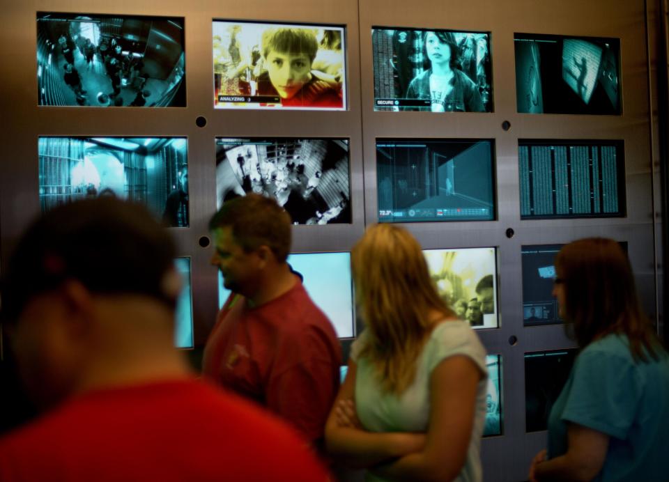 In this Friday, Aug. 9, 2013 photo, a tour group passes in front of security screens as they enter the vault containing the “secret recipe” for Coca-Cola at the World of Coca-Cola museum, in Atlanta. The 127-year-old recipe for Coke sits inside an imposing steel vault that’s bathed in red security lights, while security cameras monitor the area to make sure the fizzy formula stays a secret. (AP Photo/David Goldman)