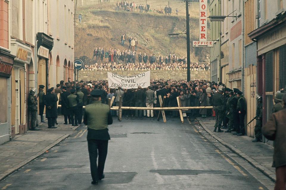 <p>Protestors stand opposite Royal Ulster Constabulary police and British soldiers at a barricade in Northern Ireland, in response to the shooting of 14 civilians by British paratroopers one week prior. </p>