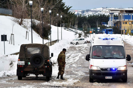 A soldier patrols a street as an ambulance drives by in the town of Penne, central Italy, following a series of earthquakes. REUTERS/Emiliano Grillotti