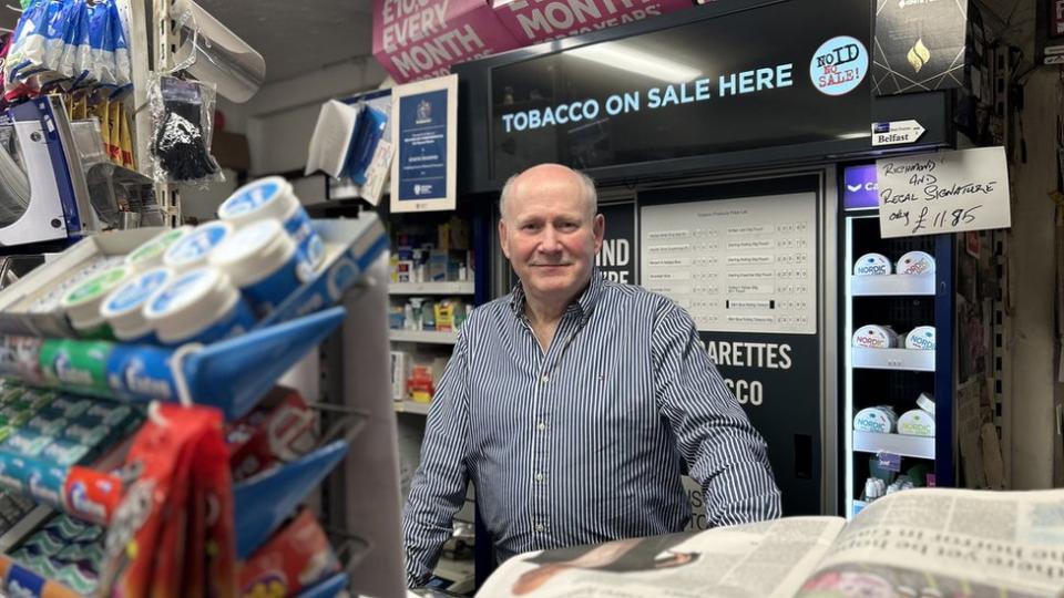 Eugene Diamond stands behind the counter in his newsagents